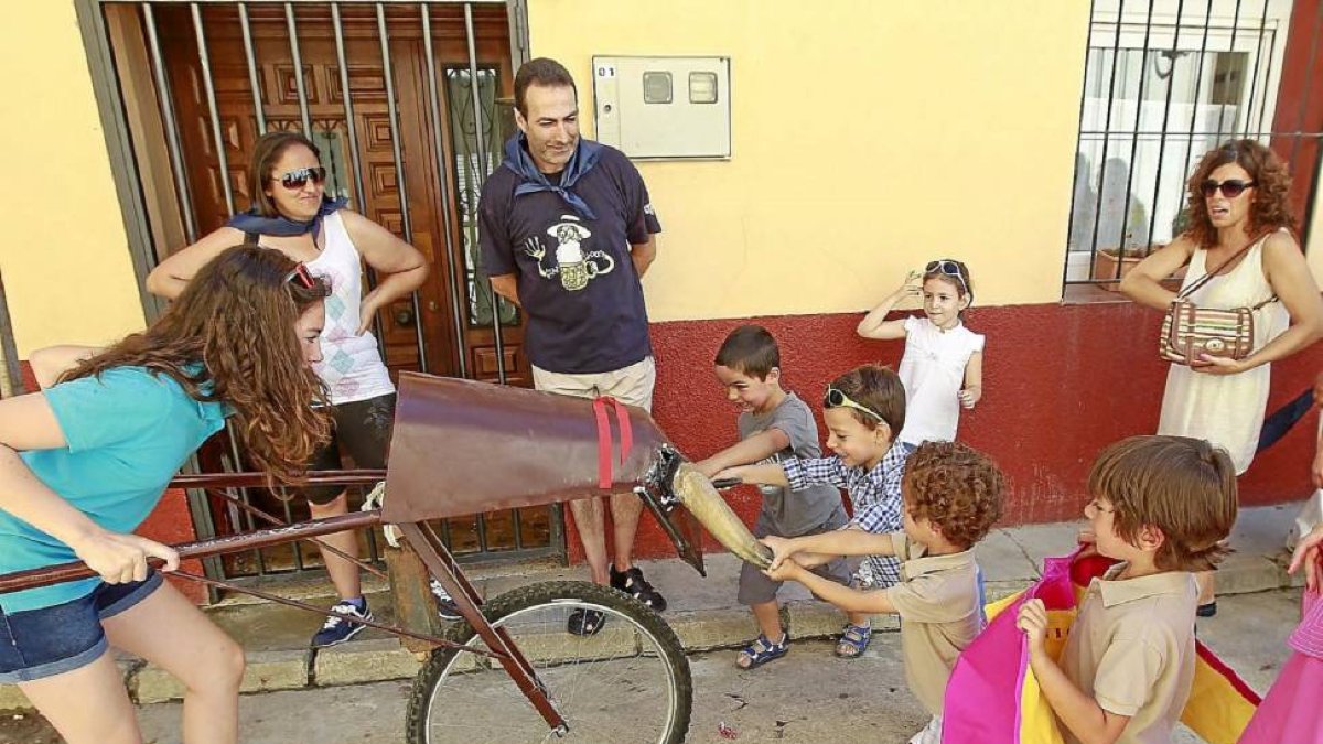 Varios niños citan con el capote y agarran los cuernos del toro.-J. M. Lostau