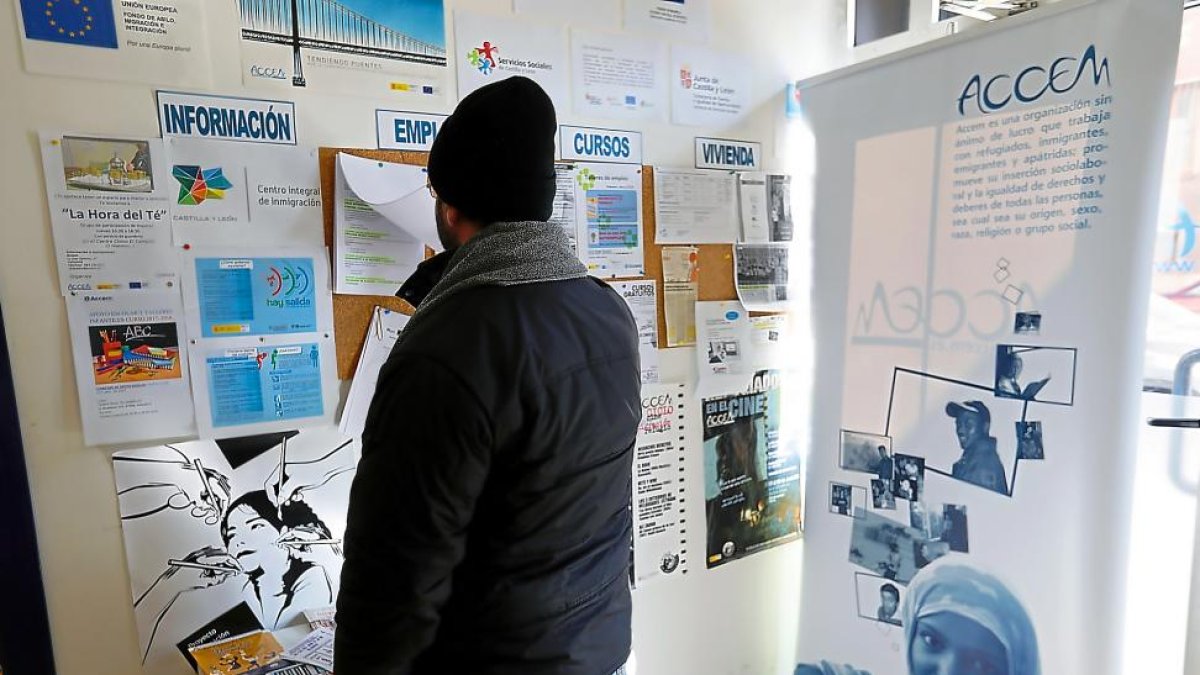 I. mira el cartel de anuncios en la sede de Accem en Valladolid.-J.M. LOSTAU