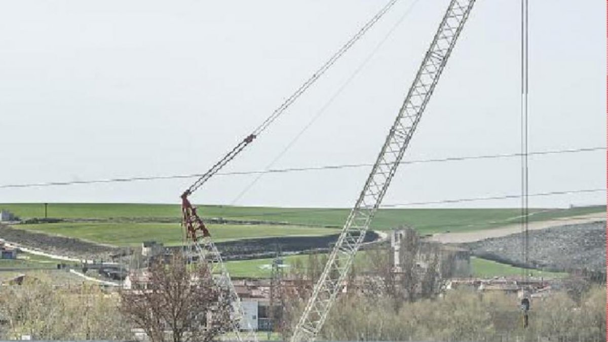 Una grúa de grandes dimensiones ha empezado a descolgar vías, barandillas y otros elementos del puente.-ISRAEL L. MURILLO