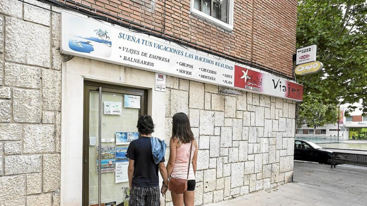 Una pareja observa las ‘ofertas’ de la agencia de viajes Vibolid el día que jue detenida la dueña, en agosto de 2014.-MIGUEL Á. SANTOS (PHOTOGENIC)