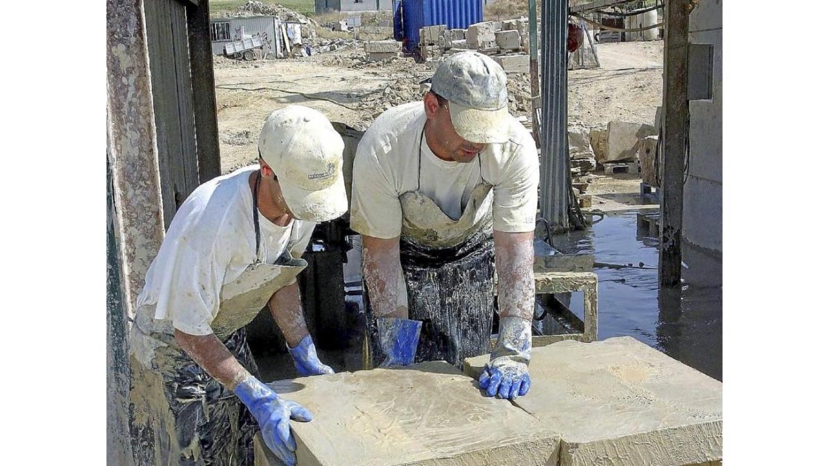 Dos operarios mueven placas de piedra en Villamayor-Ical