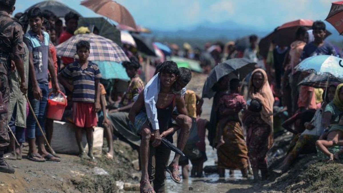 Un refugiado rohinyá lleva a cuestas a un anciano en Bangladés, cerca de la frontera con Birmania.-MUNIR UZ ZAMAN (AFP)