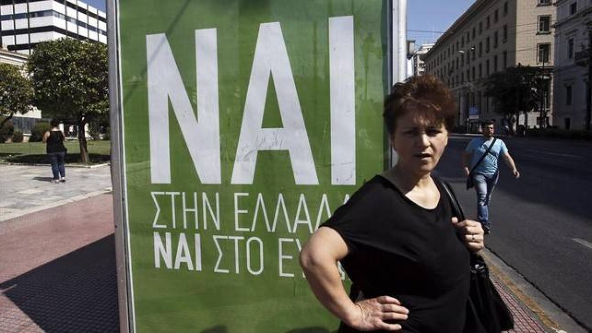 Una mujer espera el autobús junto a un cartel que pide el voto positivo en el referéndum, en el que se lee: