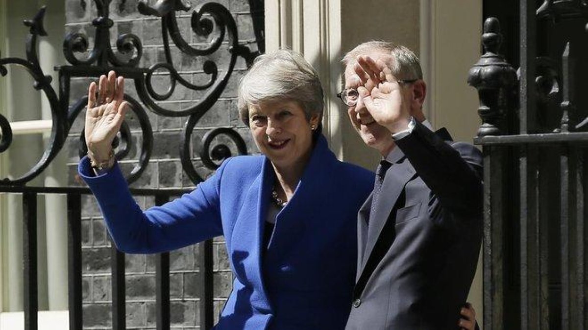 Theresa May junto a su marido Philip May saludan tras abandonar Downing Street.-AP / TIM IRELAND