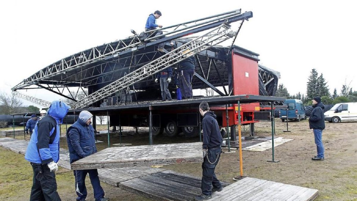 Una cuadrilla de operarios instala, ayer, el escenario principal en la campa de la antigua Hípica Militar.-J.M. Lostau