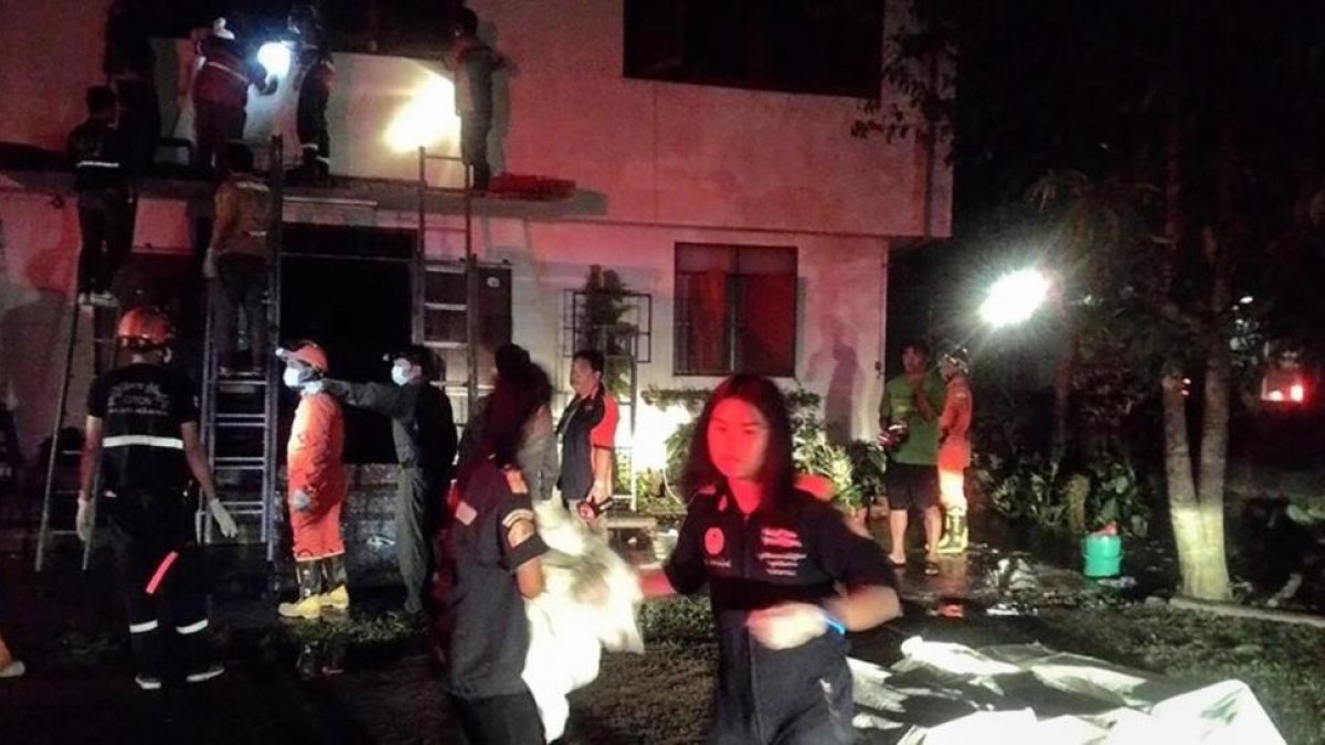 Los bomberos y policías tailandeses recuperan los cadáveres de las niñas fallecidas en el incendio del colegio.-STR