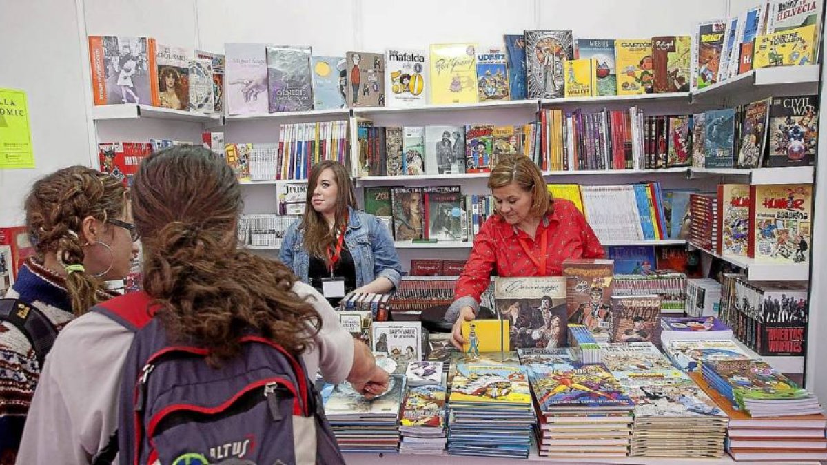 Dos jóvenes observan uno de los expositores de la Feria del Libro en la Cúpula del Milenio-Pablo Requejo
