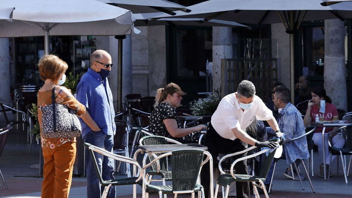 Unos clientes esperan a que el camarero desinfecte la mesa en una terraza de la Plaza Mayor. - J.M. LOSTAU