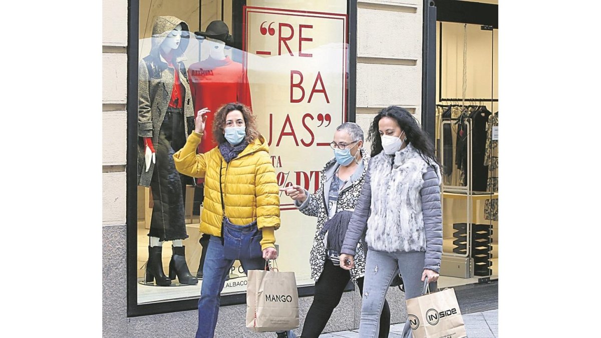 Tres compradoras pasan por delante del escaparate de una tienda que anuncia rebajas en Valladolid, ayer. J.M. LOSTAU