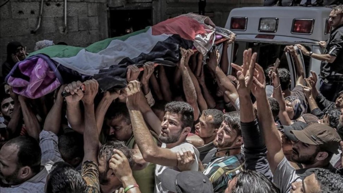 La muchedumbre traslada el féretro de Razan Najjar, la enfermera que ha muerto por los disparos hebreos. / La muchedumbre traslada el féretro de Razan Najjar, la enfermera que ha muerto por los disparos hebreos.-HAITHAM IMAD (EFE)