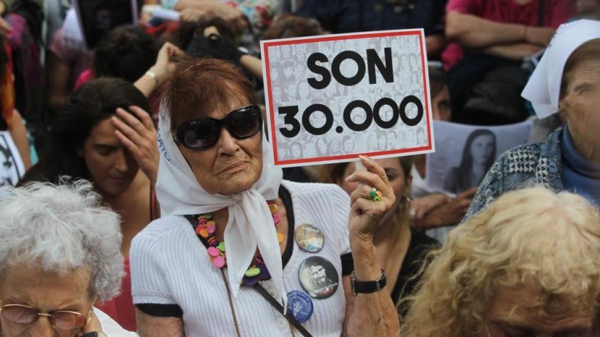 Una mujer sostiene un cartel en referencia a los 30.000 desaparecidos mientras escucha el veredicto por los crímenes cometidos en la ESMA, en Buenos Aires, el 29 de noviembre.-/ EFE / CARLOTA CIUDAD