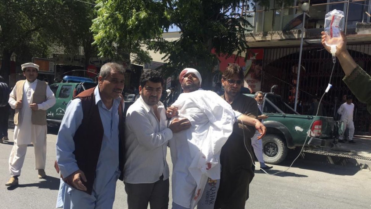 Tres personas ayudan a un hombre herido en el atentado de este miércoles en Kabul.-AP / RAHMAT GUL