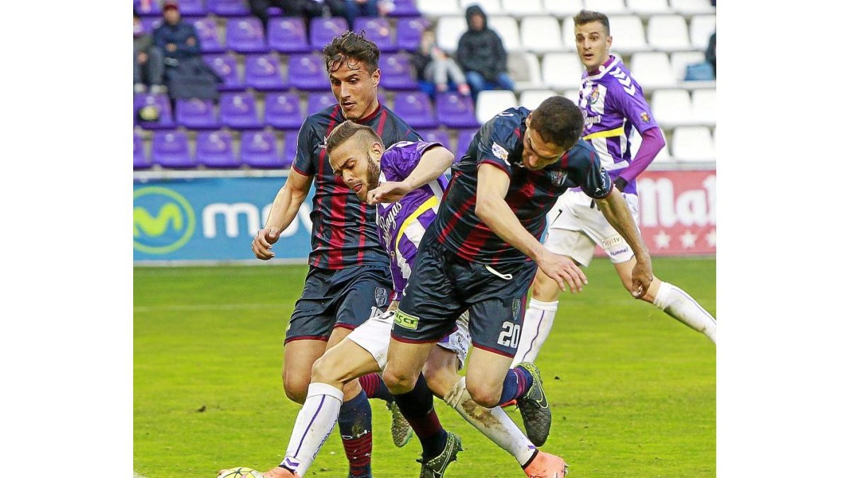 Roger puja por el control de un balón ante el acoso de Camacho y Óscar Ramírez.-J. M. LOSTAU