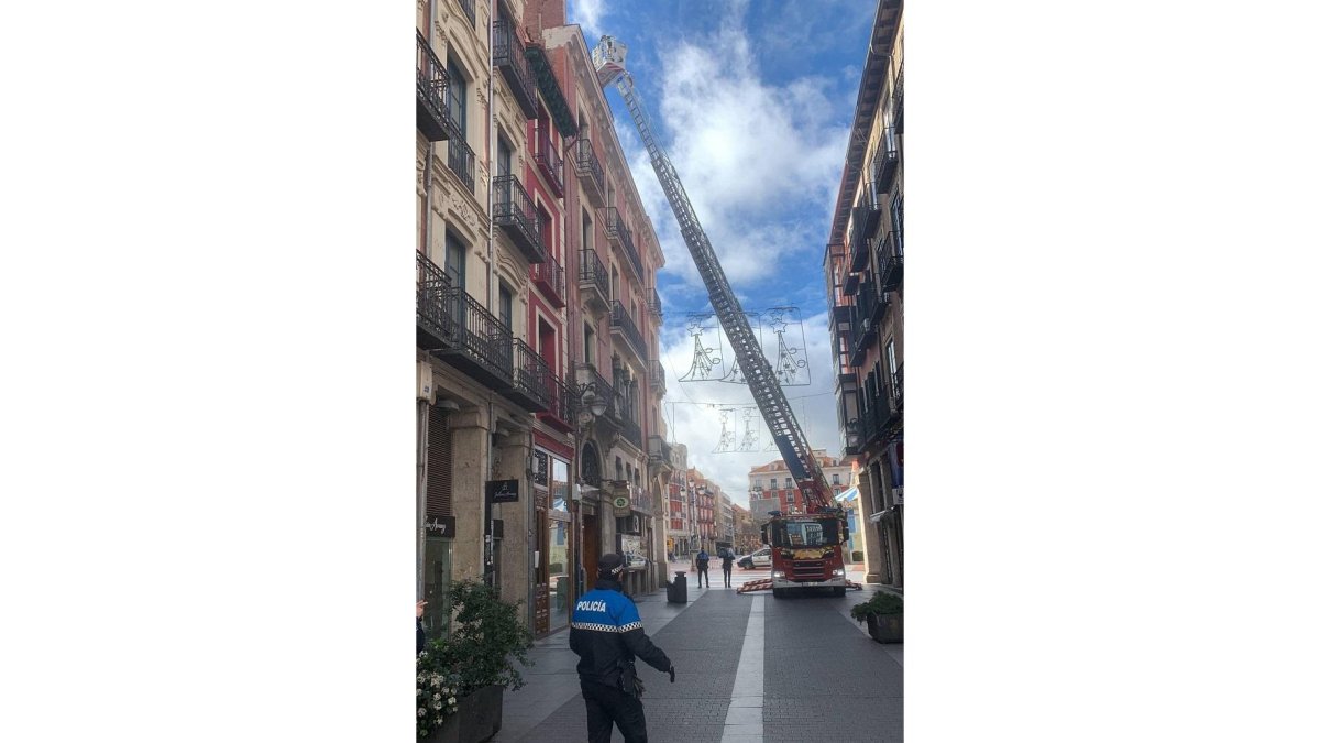 Bomberos revisan una chapa suelta en un edificio de la calle Lencería.- TWITTER POLICÍA VALLADOLID