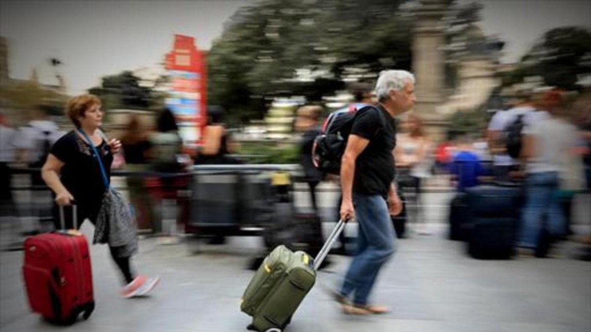 Una pareja con sus maletas y mochilas, ayer en una calle de Barcelona.-FERRAN NADEU
