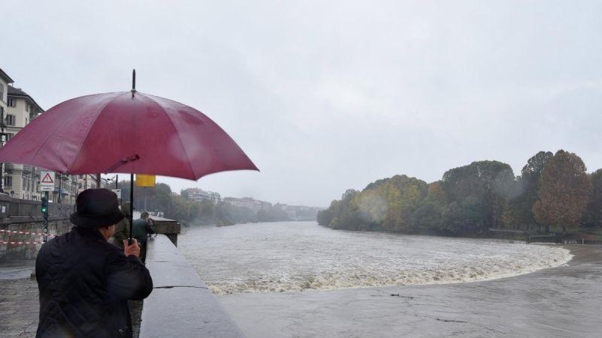 Varias personas observan la crecida del río Po durante unas fuertes lluvias en Turín. Cerca de once regiones italianas se encuentran en estado de emergencia debido a las lluvias y tormentas de los últimos días.-EPA/ANSA