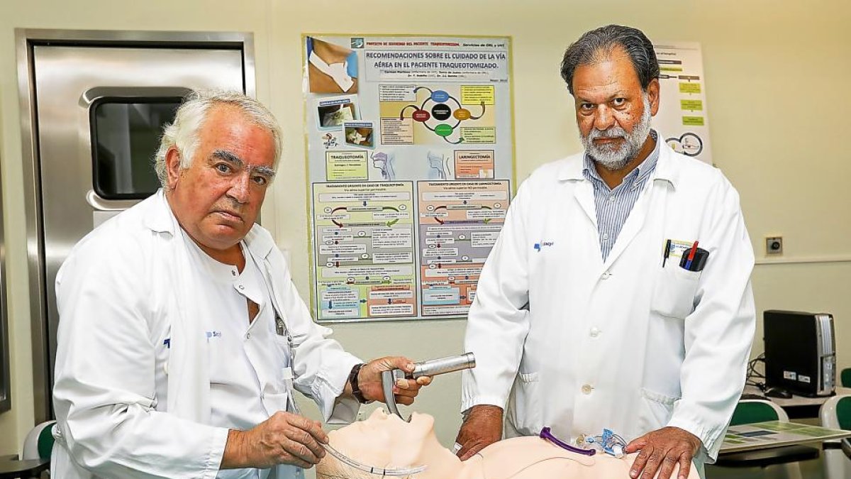 Felipe Bobillo, coordinador de la UCI del Clínico de Valladolid, y José Ignacio Benito muestran un muñeco con el que practican el cuidado de la vía aérea en el paciente traqueotomizado.-J. M. LOSTAU
