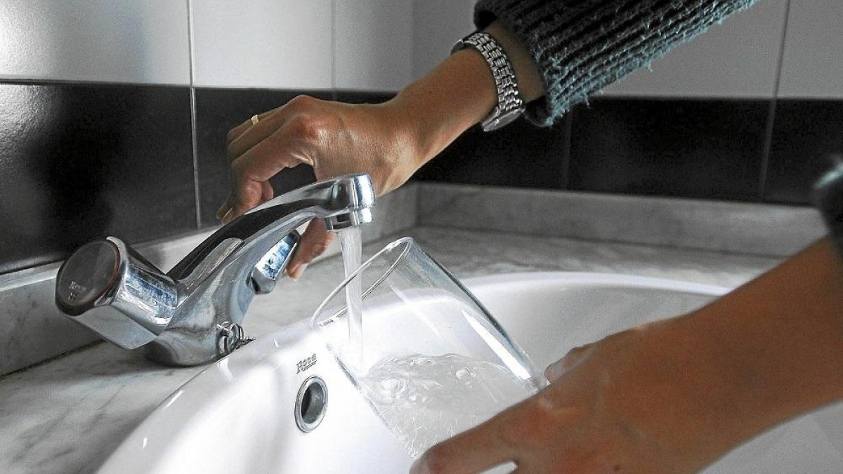 Una mujer echa agua del grifo en un vaso de cristal, en una imagen de archivo.