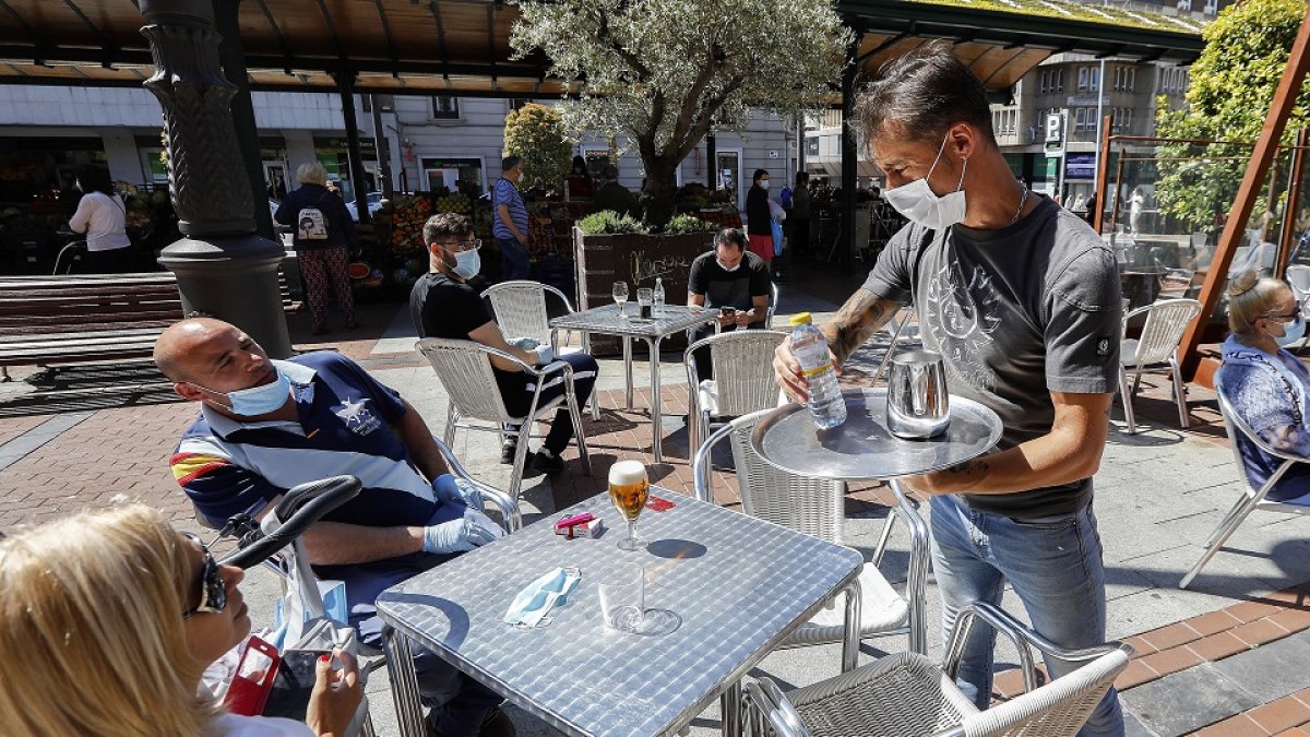 Unos clientes esperan a que el camarero desinfecte la mesa en una terraza de la Plaza Mayor. J.M. LOSTAU