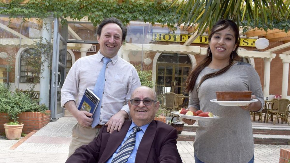 Félix, con su novela ‘Desahucio’, junto a su padre (sentado) y su pareja, Kimberly, que atiende el comedor del restaurante.-ARGICOMUNICACIÓN