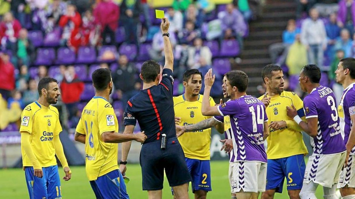 Arias López muestra la amarilla a David Simón(2) mientras los blanquivioletas piden a la roja.-J.M. Lostau