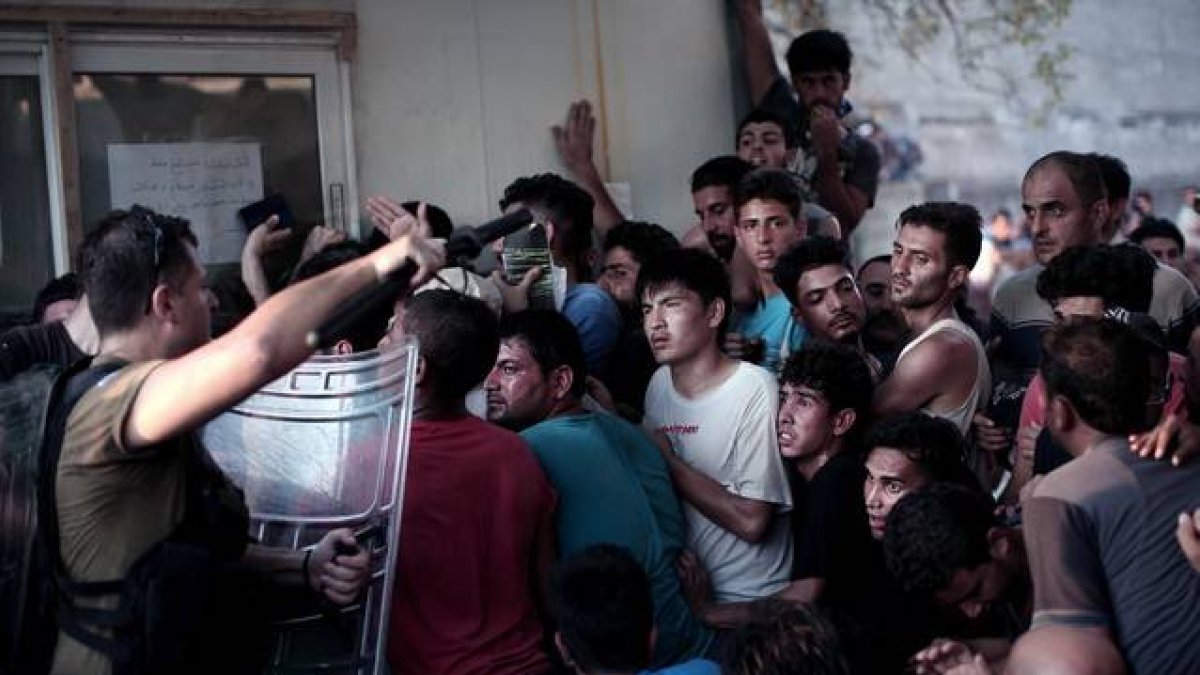 La policía helena carga contra los inmigrantes que esperan para registrarse en el puerto de Mitelene, en la isla de Lesbos.-AFP / ANGELOS TZORTZINIS