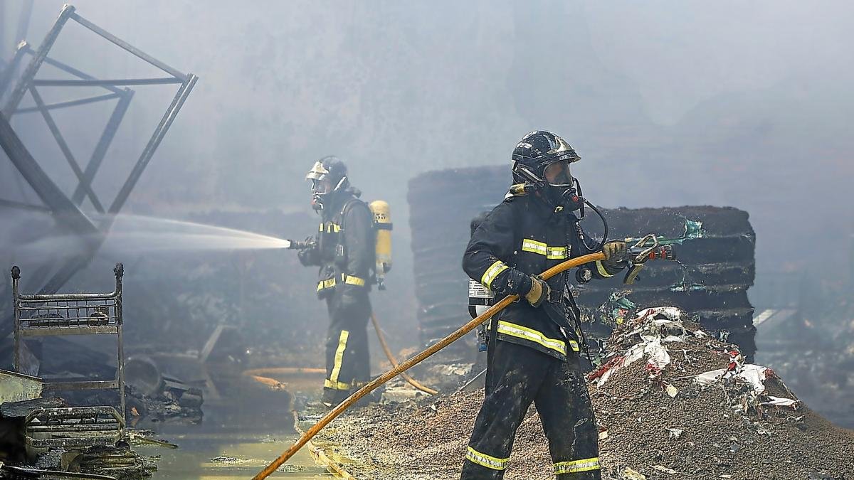 Bomberos de la Diputación este jueves, durante los trabajos de extinción del incendio en la nave de Cecoga.-J.M. LOSTAU