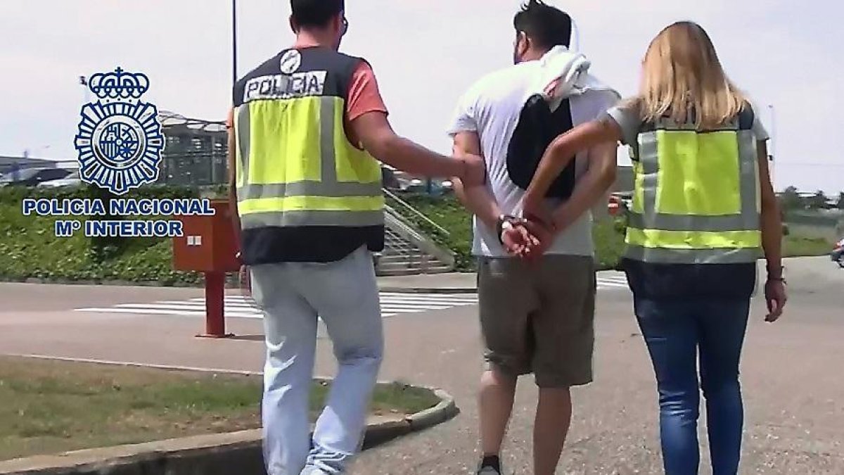 El detenido es conducido por dos agentes fuera de las instalaciones de la empresa en la que trabajaba.-E. M.