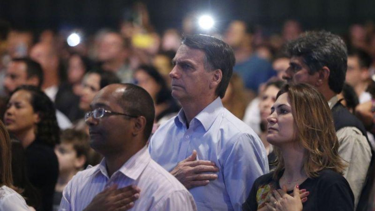 El presidente electo de Brasil Jair Bolsonaro y su esposa Michelle Bolsonaro mientras participan en un culto evangelico.-FERNANDO FRAZAO (EFE)