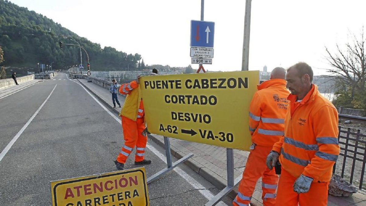 Operarios del servicio de carreteras de la Junta retiran los carteles que cortaban el paso en el puente medieval de Cabezón.-J. M. Lostau