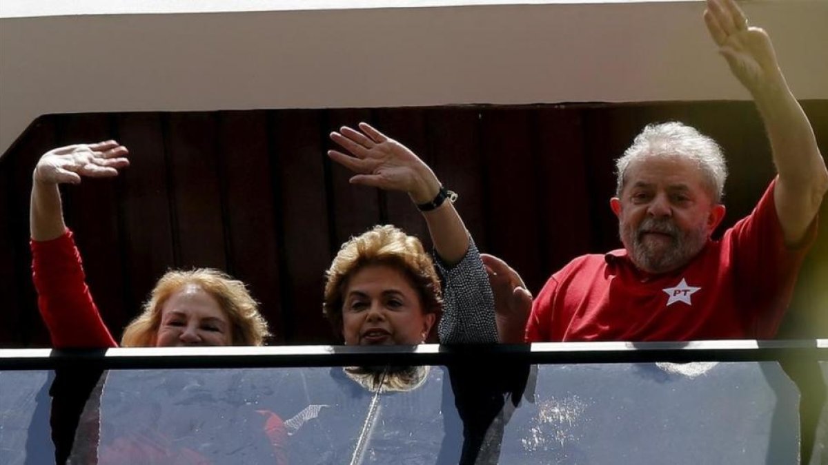 Lula (derecha), Rousseff y la esposa del expresidente, Marisa, saludan desde una ventana de la casa de la parella, en Sao Bernardo do Camopo (Brasil), el 5 de marzo.-REUTERS / PAULO WHITAKER