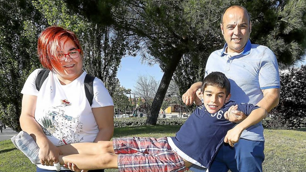 Ambos padres, Marta y Jairo, sostienen al incansable Pablo de pies y manos, mientras que juegan juntos como cada día.-J.M.LOSTAU