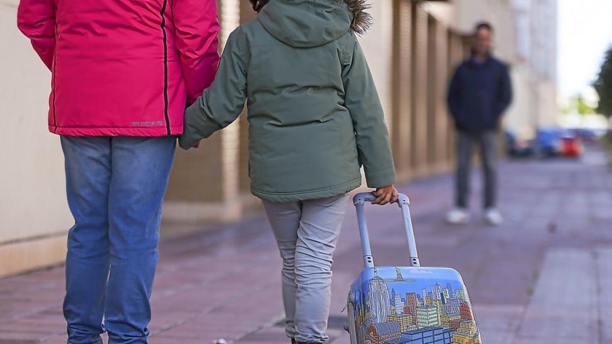 Una niña camina portando una maleta entre sus progenitores.-MIGUEL ÁNGEL SANTOS (PHOTOGENIC)