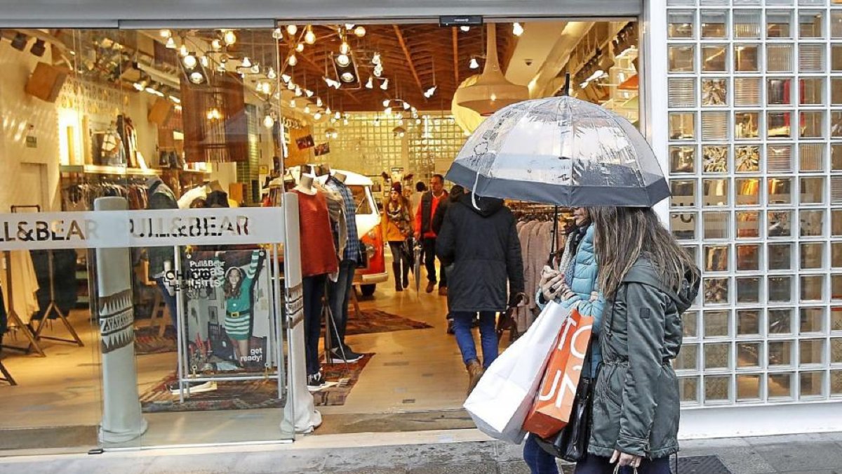 Dos mujeres pasan ante una de las tiendas que abrió ayer domingo.-J.M. Lostau
