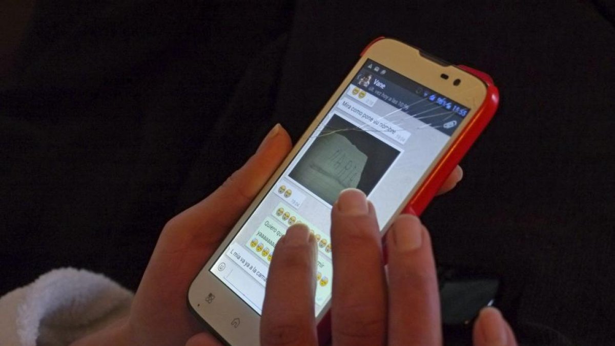 Una joven chatea con su teléfono móvil.-EL MUNDO