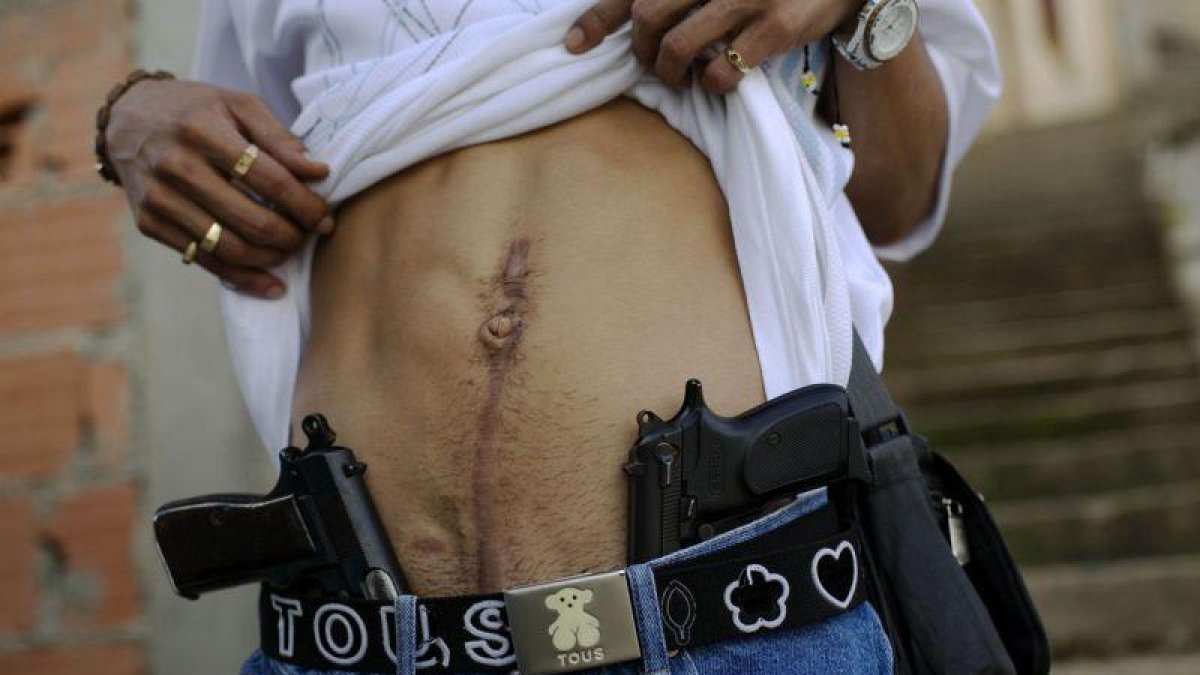Un traficante de drogas muestra su herida de bala y su arma en Caracas.-Rodrigo Abd / AP