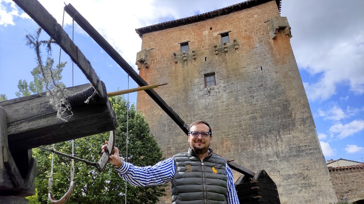 Millán Bermejo, apoyado en una recreación de un arma de asedio medieval, frente al Torreón de Fernán González de Covarrubias.