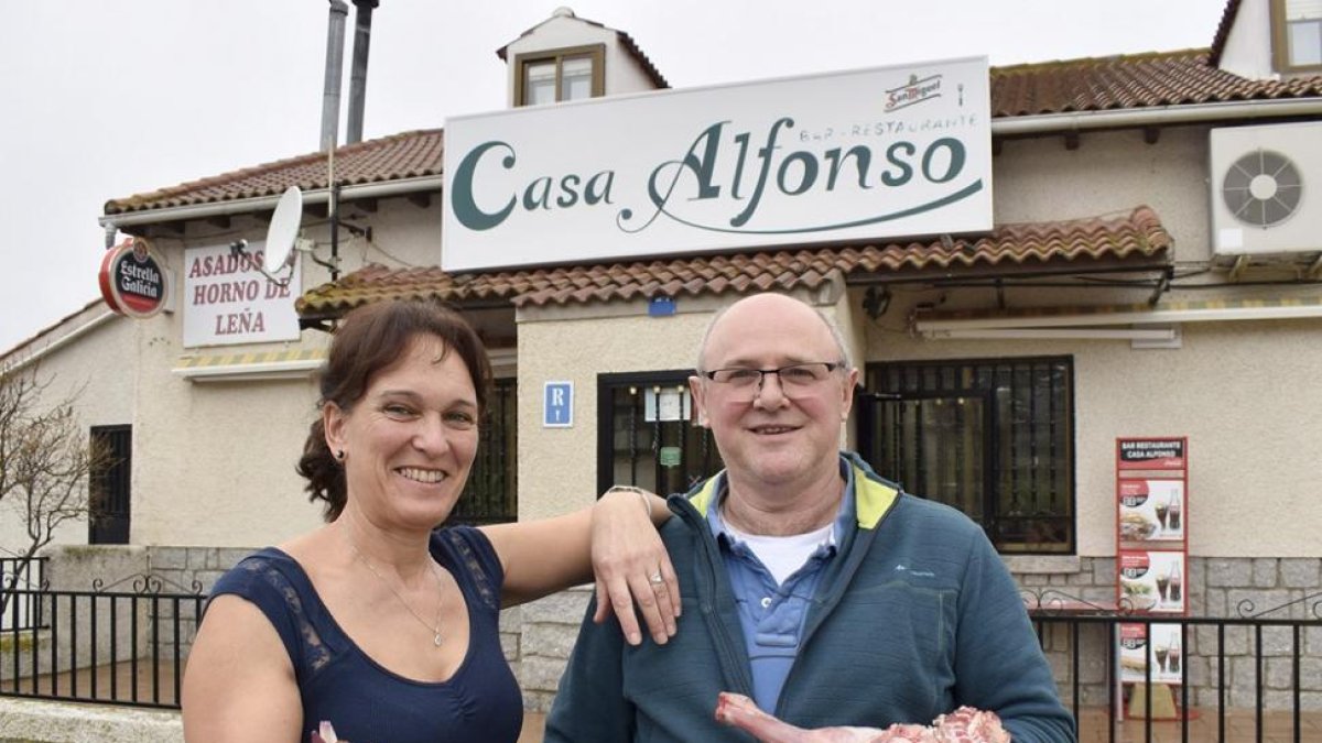 Alfonso y Alicia, con las patatas revolconas y una pieza de carne, a la entrada del establecimiento.-ARGICOMUNICACIÓN