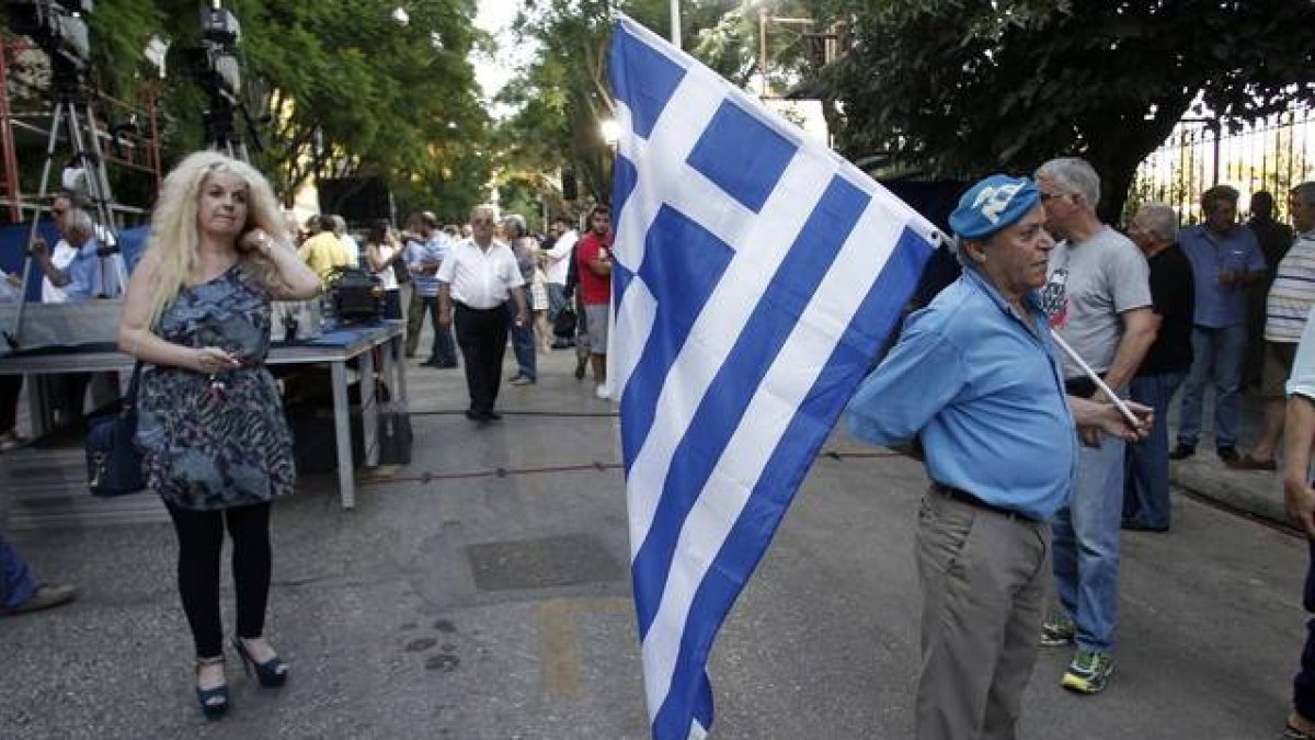 Un simpatizante del partido conservador de Nueva Democracia sale a la calle vestido de azul y con la bandera griega, a 20 días de las elecciones generales.-EFE / ALEXANDROS VLACHOS