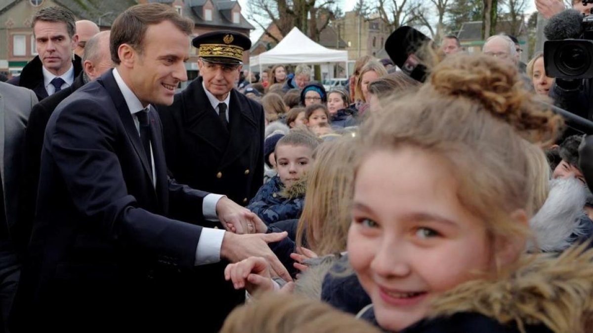 Macron saluda a los residentes a su llegada a un centro de migrantes en Croisilles, en el norte de Francia, el 16 de enero.-EFE / MICHEL SPINGLER