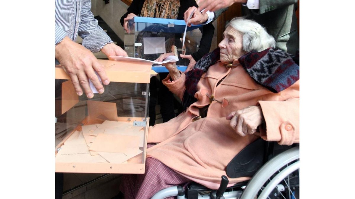 Una señora mayor en silla de ruedas vota a las puertas del colegio Santa Teresa de Jesús al no estar habilitado para discapacitados-Ical