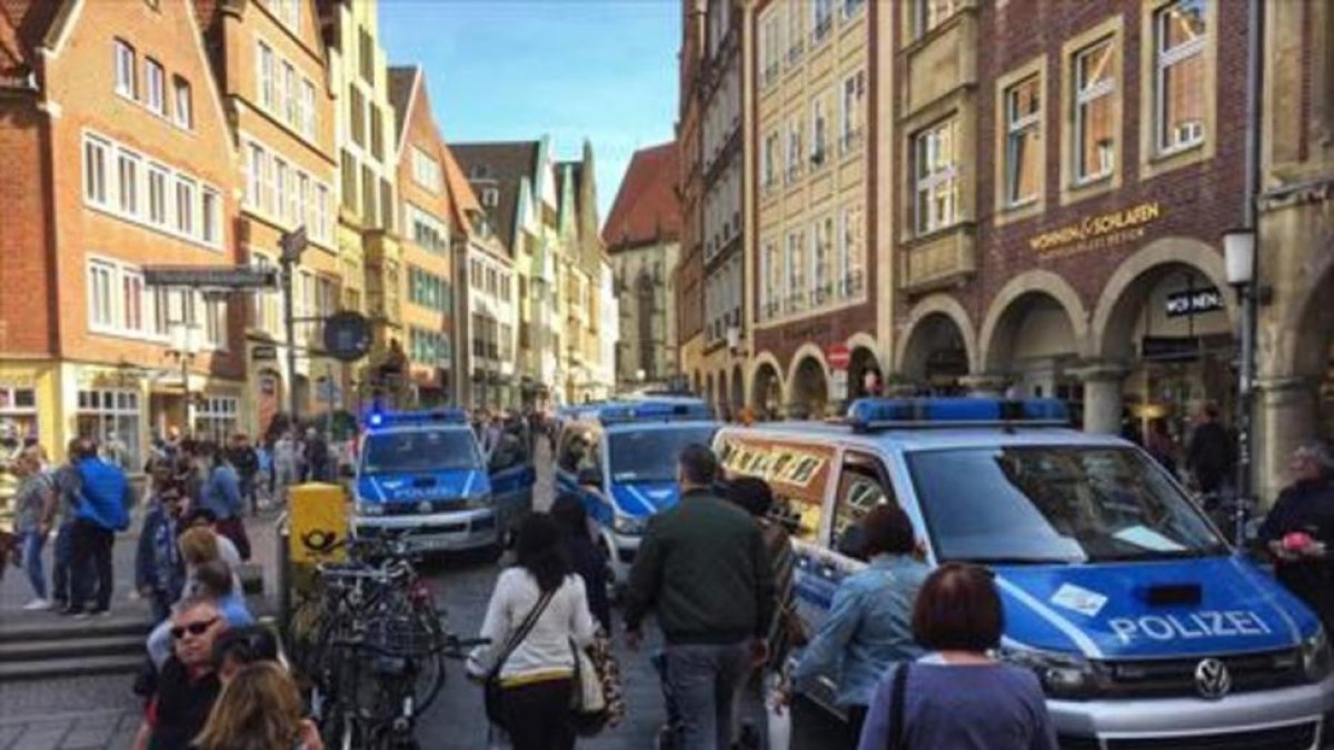 Vecinos y turistas circulan por el centro de Münster, entre furgonetas de la policía, tras el atropello de ayer.-/ AFP
