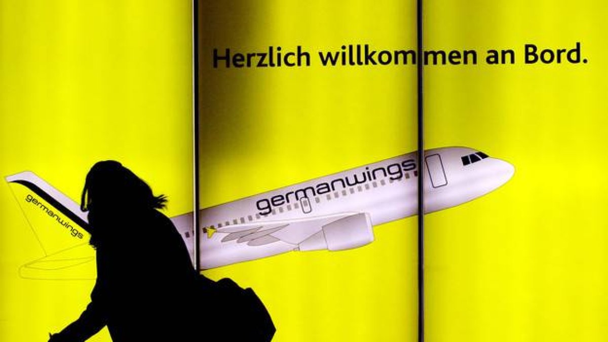 Una mujer pasea por delante de un cartel publicitario de Germanwings en el aeropuerto de Colonia, en Alemania.-Foto:   OLIVER STRATMANN / AFP