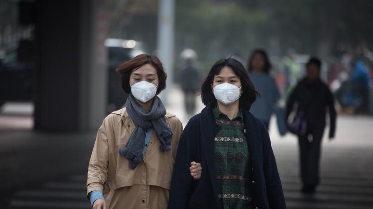Dos mujeres con mascarilla caminan por la calle en Pekín (China).-EFE