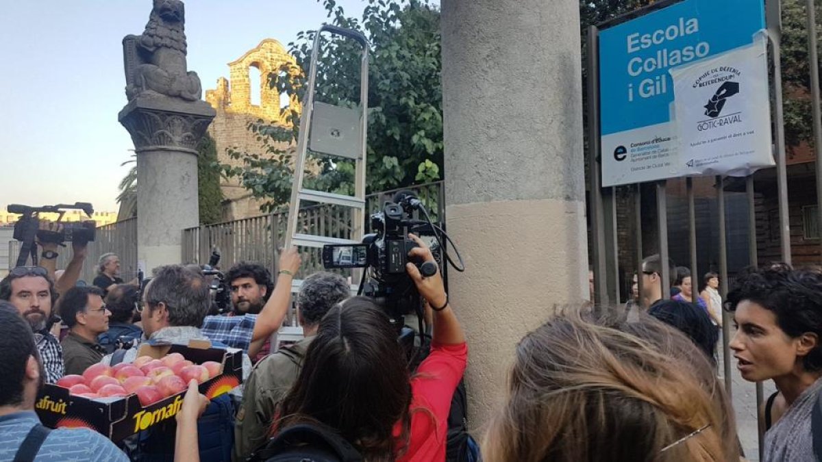 Los mossos se han ido y varias personas entran la escuela Collaso i Gil con la ayuda de una escalera entre aplausos-ROGER PASCUAL