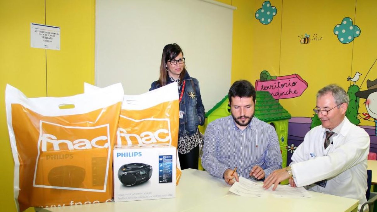 El director médico del Hospital Universitario Río Hortega, José Miguel García Vela y al representante de FNAC, Víctor Fuentes Brea, firman el acuerdo ante la responsable de marketing de Río Shopping, Sara Valladolid-ICAL