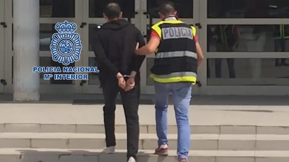 Un agente de la policía se lleva detenido al sospechoso.-ICAL