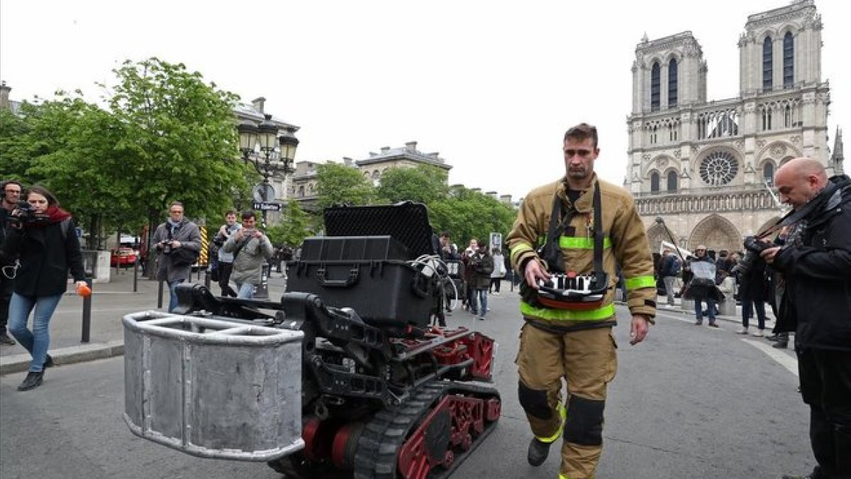 Un bombero, junto con el robot que ayudó a los bomberos en el incendio de Notre Dame, este martes.-REUTERS / YVES HERMAN