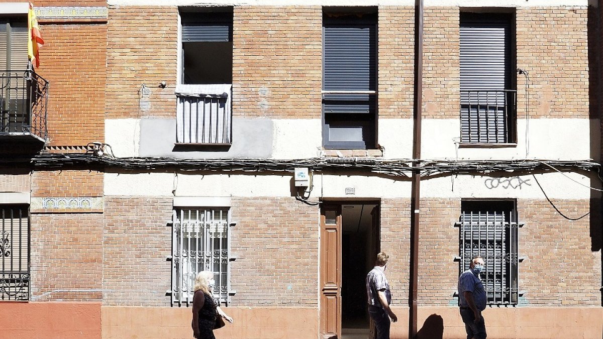 Vecinos pasan delante de uno de los portales de Padre Manjón donde hay familias aisladas. PHOTOGENIC/M. Á. SANTOS