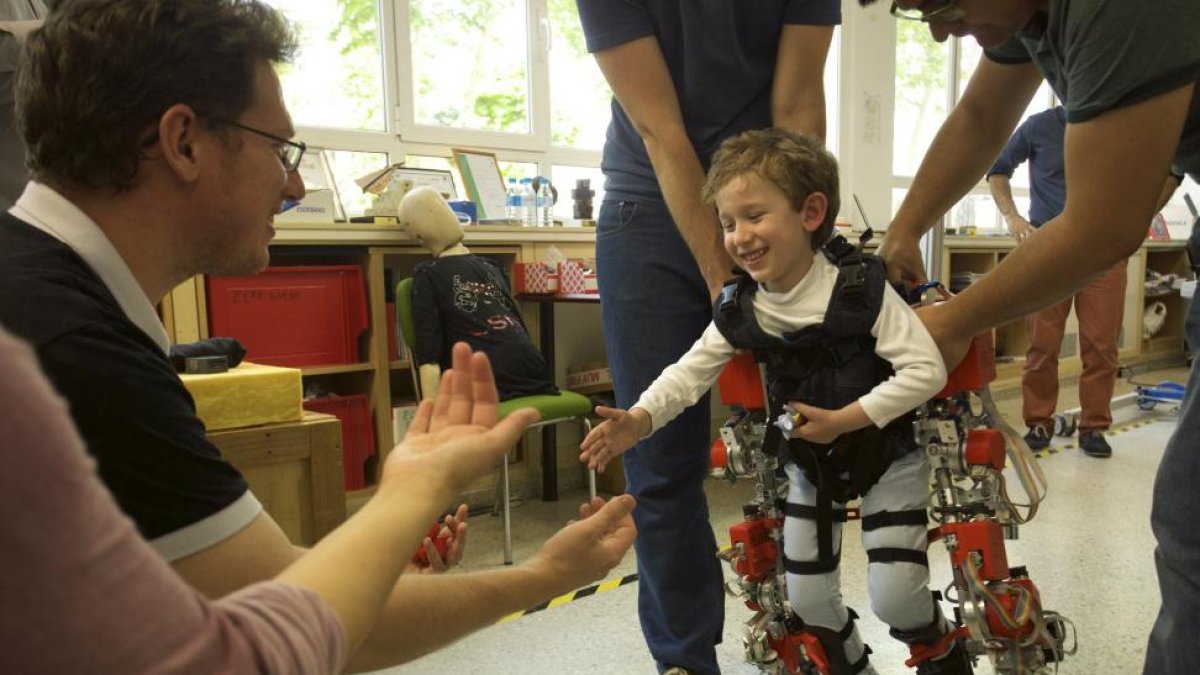 El pequeño Álvaro vestido con el exoesqueleto se lanza hacia su padre en una de las pruebas del dispositivo biónico, que le permite ponerse en pie y caminar.-CSIC